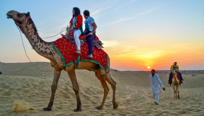 a man and woman riding a camel in the desert