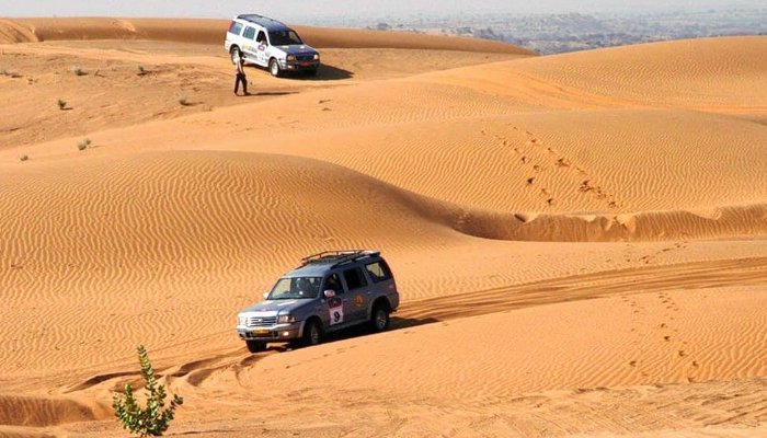 two vehicles driving through the desert